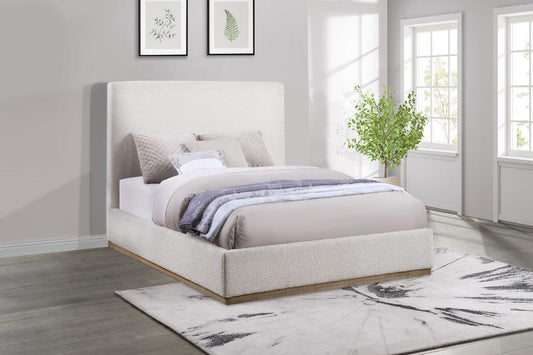 Neatly made boucle bed in a bedroom with light gray walls, a rug, and framed pictures.